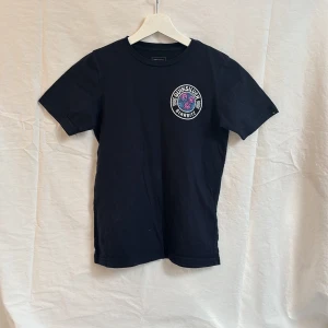 Svart t-shirt från Quiksilver med tryck - Mörk blå t-shirt från Quiksilver med färgglatt tryck på bröstet och ryggen 