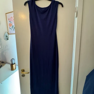 Marinblå långklänning med öppen rygg -  Klänningen har en tight passform och öppen rygg. 