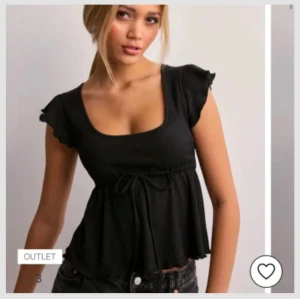 Svart topp med volangärm från Nelly - Säljer en svart topp från Nelly i storlek XXS. Toppen har korta volangärmar, rundad urringning och knytband i midjan. Materialet är ribbat och toppen har en lätt utsvängd passform nedtill.