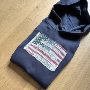 Mörkblå hoodie från Ralph Lauren med amerikansk flagga - Tja! Säljer en sjukt snygg Ralph Lauren Hoodie med amerikansk flagga. Storlek M men passar en S. Vid frågor är det bara att höra av sig