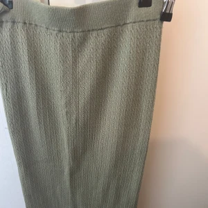 Olivgrön stickad kjol från Zara - Olivgrön stickad kjol från Zara med ribbad midja. Kjolen har en rak och enkel design som ger en stilren look. Säljer tillhörande väst separat 