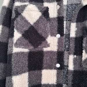 Rutig teddyjacka från KappAhl - Mysig teddyjacka från KappAhl i svart, grått och vitt rutigt mönster. Jackan har långa ärmar, bröstfickor och stängs med tryckknappar. Perfekt för kyliga dagar och ger en avslappnad look. Använd 1 gång när den skulle testas hemma, jättebra skick men en liten fläck på fickan man inte märker!💞