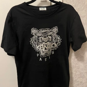   Kenzo  t-shirt - Svart t-shirt från Kenzo med ikonisk tigerbrodyr och texten 'KENZO PARIS' framtill. Klassisk rund halsringning och korta ärmar. Perfekt för dig som vill ha en statement-piece i garderoben.