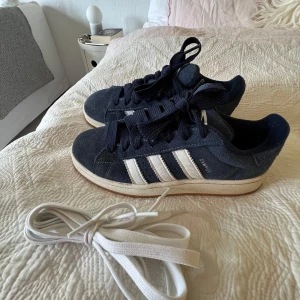 Adidas Campus i marinblå mocka - Säljer mina Adidas Campus sneakers i marinblå mocka (de är impregnerade) i storlek 39 och 1/3. De är köpta från Zalando i februari i år, för 1449kr men är bara använda ett fåtal gånger eftersom de inte passar mig tyvärr. Kan skicka fler bilder om det önskas! Finns även med ett par extra oanvända vita skosnören💕 
