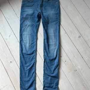 Blå jeans från Jacob Cohen - Säljer ett par klassiska blå jeans från Jacob Cohen i modellen Kimberly. Byxorna har normal passform, dragkedja och knappdetaljer framtill. Snygga sömmar och en bakficka. Perfekta för dig som gillar stilrena jeans med exklusiv känsla.