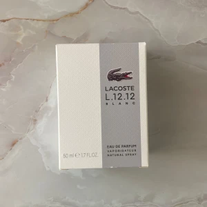 Lacoste L.12.12 Blanc Eau de Parfum 50ml - Fräsch och sportig parfym från Lacoste i en stilren vit flaska med texturerad yta och klassisk krokodil-logga. Doften är modern och maskulin, perfekt för dig som gillar rena och eleganta toner. Flaskan rymmer 50 ml Eau de Parfum.