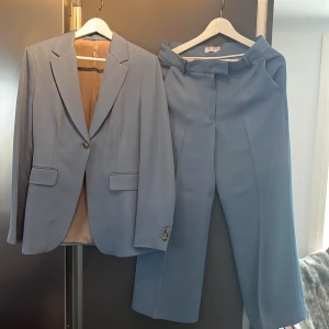 Ljusblå kostym från Tiger of Sweden - Snygg ljusblå kostym från Tiger of Sweden med klassisk kavaj och matchande byxor. Kavajen har två knappar och fickor framtill, samt ljus innerfoder. Perfekt för dig som vill sticka ut med stilren look.