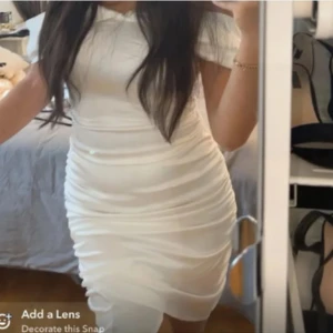 HELT NY Studentklänning - Vit off shoulder klänning i satin från Nelly märket parisian. Klänningen är tight och har en draperad design med slits framtill. Perfekt till student, prislapp sitter fortfarande kvar. Storlek 36.