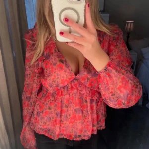 Blommig rosa blus  - Säljer en blommig blus i rosa och lila toner med volangdetaljer och v-ringning från Bikbok i storlek S.