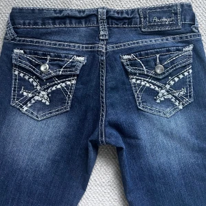 Blå bootcut jeans  - Snygga blå jeans från Amethyst med bootcut passform. Jeansen har broderade bakfickor med dekorativa knappar och ljusa slitningar framtill. Låg midja. Lite slitage längst ner. Skriv för fler bilder eller frågor!🤍💙🩵