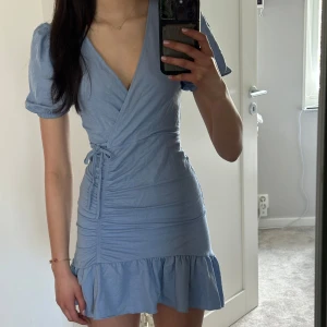 Ljusblå omlottklänning - Hej! Jag säljer denna omlottklänningen från GinaTricot som passar perfekt nu till sommaren! Klänningen är k storlek xxs men jag skulle säga att den passar en xxs-xs. Tveka inte på att skriva vid frågor och pris kan diskuteras!🤗