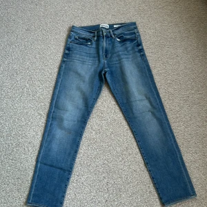 Blå jeans frame L'Homme Straight - Säljer ett par klassiska blå jeans från frame L'Homme i modellen Straight. Jeansen har fem fickor, normal passform och raka ben. Perfekta för dig som gillar en tidlös stil. Midjan är normal och materialet är slitstarkt denim.