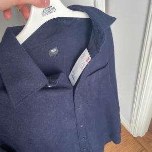 Mörkblå skjorta från Uniqlo - Säljer en splitterny och casual mörkblå skjorta från Uniqlo. Perfekt för en clean, casual och lite laidback look. Hör av dig vid funderingar!