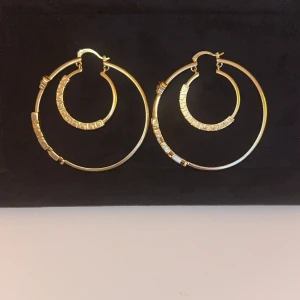 Guldörhängen med grekisk nyckeldesign - Snygga guldörhängen i creolstil med en unik grekisk nyckeldesign. De har en elegant och modern look som passar perfekt för att lyfta vilken outfit som helst.