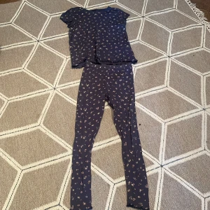 Blommigt set med topp och leggings - Säljer ett matchande set med en blommig topp och leggings. Toppen är kortärmad och har en söt volangdetalj vid ärmslut och nederkant. Leggingsen är i samma blommiga mönster och har en bekväm passform. Perfekt för en avslappnad dag hemma eller ute.