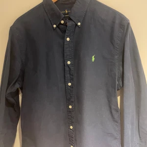 Mörkblå skjorta från Ralph Lauren - Säljer en mörkblå skjorta från Polo Ralph Lauren med broderad logotyp på bröstet. Skjortan har inga defekter! . Perfekt för sommaren! pris går självklart att diskuteras.