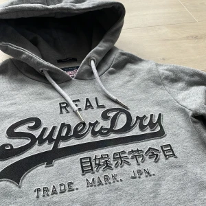 Superdry Hoodie - Säljer nu en schysst hoodie från Superdry. Hoodien är i toppskick 9/10, och inga defekter förekommer. Storlek S, men något mindre i storleken. Hör av dig vid intresse! 💫