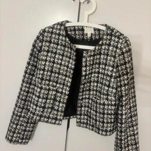Svartvit rutig tunn jacka från H&M - Snygg svartvit rutig jacka från H&M i en klassisk design. Jacka har en croppad passform och är stilren. Den ä använd cirka 5 ggr i sin höjd!!