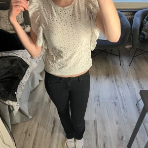 Vit blus med spetsdetaljer - Säljer en söt vit blus med spetsdetaljer och volangärmar. Perfekt för en somrig look. Blusen har ett fint hålmönster som ger en luftig känsla.