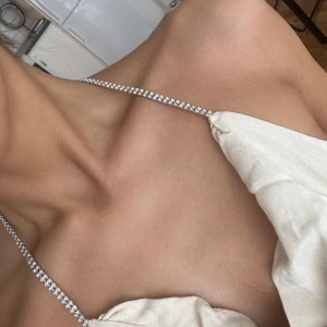 Beige klänning från Zara - Snygg beige klänning från Zara med glittriga axelband och draperad framsida. Klänningen har en öppen rygg. I sidenaktigt material. Två små fläckar på baksidan (se sista bild), försvinner i tvätt 🤍 har fler annonser uppe med billiga kläder/väskor