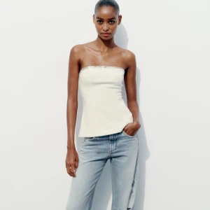 Vit tubtopp med glittrig kant - Såå snygg vit tubtopp med en glittrig kant upptill från Zara. Den är helt oanvänd och har inga defekter. En perfekt topp nu till våren och sommaren! Skriv gärna till mig om du har några funderingar eller liknande💕💕🤍🌟