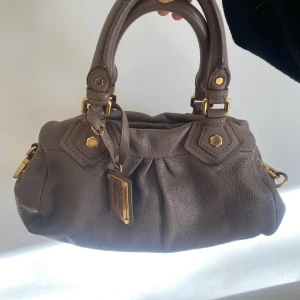 Marc jacobs väska  - Brun/grå aktig marc jacobs väska i modellen Baby groove. Fint skick + band medföljer