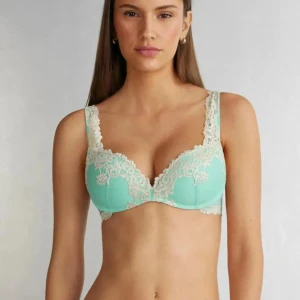 Turkos Intimissimi bh  - Säljer en vacker mintgrön bh med spetsdetaljer. Bh:n har justerbara axelband och en elegant design med blommönster i spetsen. Perfekt för att känna sig extra fin. I storlek 70B. Har ett brännmärke i vadderingen 