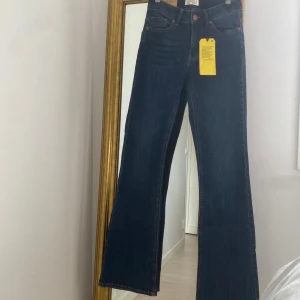 Blå bootcut jeans från Lindex - Snygga blå bootcut jeans från Lindex helt oanvänd , i modell Karen. De har en hög midja och klassisk femficksdesign med knapp och dragkedja framtill. Perfekta för en stilren look. 