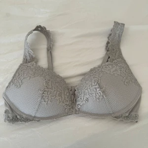 Grå spets-bh - Säljer en elegant grå bh med vacker spetsdetaljering. Bh:n har justerbara axelband och en klassisk knäppning bak. I storlek 80b tror jag