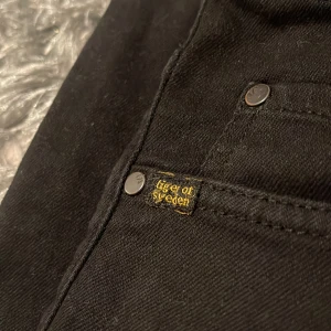 Svarta jeans från Tiger of Sweden - Snygga svarta jeans från Tiger of Sweden med klassisk design. De har en normal passform och är tillverkade i ett slitstarkt material. Perfekta för en stilren look.