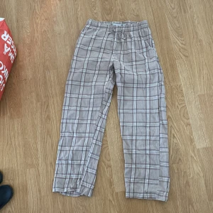 Beige rutiga byxor  - Säljer ett par bekväma beige rutiga byxor från 157. Byxorna har en elastisk midja för extra komfort och är perfekta för en avslappnad stil. De är tillverkade i ett mjukt material som känns skönt mot huden. 