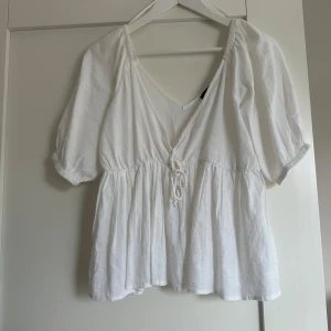 Vit blus med knytning - Säljer en söt vit blus med korta ärmar och v-ringning. Blusen har en knytning framtill och är i väldigt bra skick. Pris kan diskuteras, hör av er vid frågor!❣️