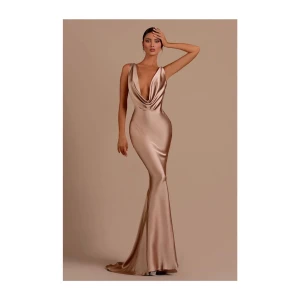 Champagnefärgad långklänning i satin - Elegant champagnefärgad långklänning i satin med djup v-ringning och öppen rygg. Klänningen har en draperad design som ger en lyxig känsla. Perfekt för speciella tillfällen. Jag köpte denna till min bal men tyvärr var den för kort för mig och slutade lite högre än vad jag hade önskat. För referens är jag 175 cm. Helt ny och oanvänd men lappar kvar. Köpt för 1600kr. 