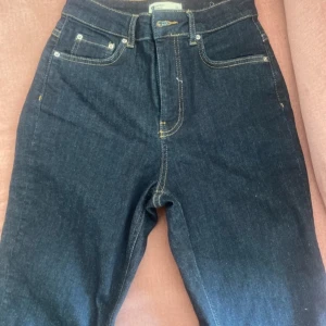 Mörkblå  jeans med snygg benform.  -  mörkblå jeans med hög midja och raka ben med snygg benform. Klassisk femficksdesign. Storlek 34 