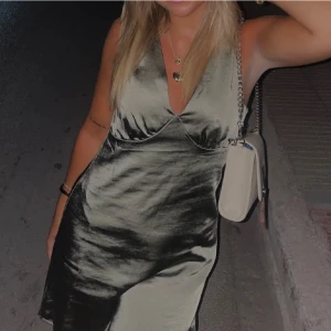 Grön satin klänning - Snygg grön axelbandslös klänning i satin med v-ringning. Perfekt för en kväll ute eller en speciell tillställning. Klänningen har en elegant och stilren design.