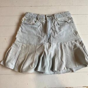 Ljusblå jeanskjol med volang - Säljer en ljusblå jeanskjol med volangdetaljer. Kjolen har en klassisk femficksdesign och stängs med dragkedja och knapp framtill. Perfekt för en avslappnad stil. Pris kan diskuteras vid snabb affär!