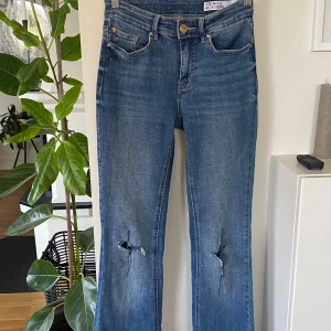 Blå jeans med slitningar! Flared! Lågmidjade!  - Snygga blå jeans med slitningar på knäna. De har en klassisk femficksdesign och en knappgylf. Perfekta för en avslappnad stil! VMFLASH MR FLARED 