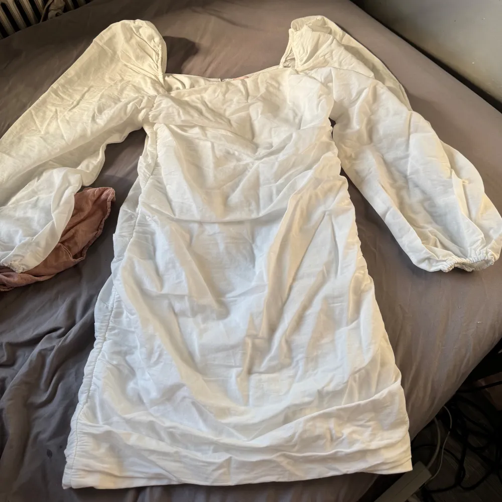 ( Helt ny och aldrig använd, prislappen är kvar!!) Säljer en elegant vit student klänning med långa puffärmar och dragkedja i ryggen. Från Nelly i storlek L. Mekot.