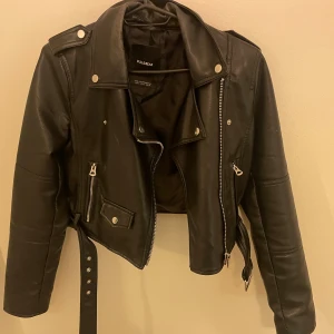 Svart skinnjacka från Pull&Bear - Snygg svart skinnjacka från Pull&Bear med dragkedja och knappar. Jackan har flera fickor med dragkedjor. Säljer denna för det inte kommer till användning 💕