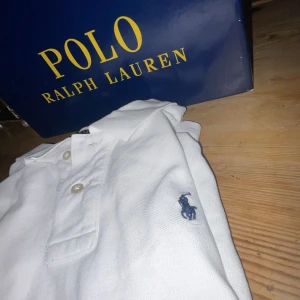  pikétröja polo Ralph Lauren - Säljer en klassisk vit pikétröja från Ralph Lauren med den ikoniska loggan broderad i blått på bröstet. Tröjan har en knappslå med två knappar och är perfekt för en stilren look. Passar både till vardags och mer uppklädda tillfällen. Säljer lågt pga att den säljs inte. Pris kan diskuteras 