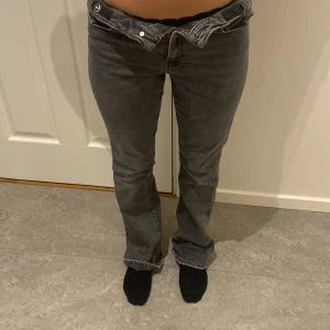 Grå jeans med bootcut - Snygga grå jeans med bootcut-stil och låg midja. De har en klassisk femficksdesign och stängs med dragkedja och knapp. Perfekta för en avslappnad look.