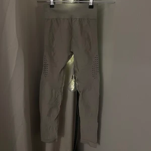 Beige tights med ribbade detaljer från Capatree - Snygga beige träningsbyxor med ribbade detaljer och perforeringar längs benen. Från Capatree