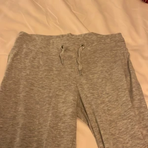 Grå mjukisbyxor med snörning - Säljer ett par bekväma grå mjukisbyxor med snörning i midjan. Perfekta för en avslappnad dag hemma eller på språng. De har en enkel och stilren design som passar till det mesta.