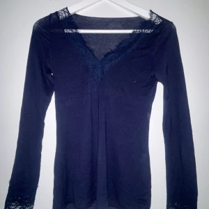 Mörkblå långärmad topp från Intimissimi🫶🏽 - Elegant svart långärmad topp från Intimissimi med spetsdetaljer vid halsringningen. Perfekt för en stilren look. Tillverkad i mjukt material för extra komfort.