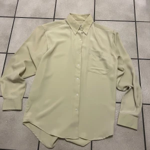 Beige skjorta från Vegas - Säljer en stilren beige skjorta från Vegas med klassisk krage och knappar framtill. Skjortan har en bröstficka och långa ärmar med knappar vid ärmsluten. Perfekt för en elegant look.