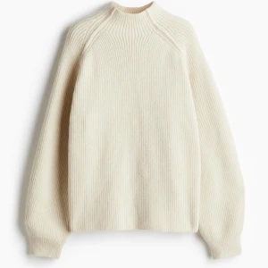 Beige stickad tröja från H&M - Säljer en stilren beige stickad tröja från H&M. Tröjan har en hög krage och långa ärmar, perfekt för kyligare dagar. Den ribbade designen ger en klassisk look som passar till det mesta. Perfekt för både vardag och mer avslappnade tillfällen.