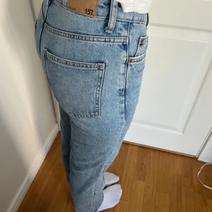 Blå jeans med knappar - Snygga blå jeans med hög midja och knappgylf. Klassisk femficksdesign och raka ben för en tidlös look. Perfekta för en avslappnad stil.