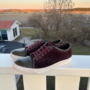 Lanvins uk 10 passar 44/45 - Snygga vinröda sneakers från Lanvin med mockaöverdel och glansiga tåhättor. Skorna har en vit sula och matchande vinröda snören. Perfekta för en stilren look. Priset går att diskutera vid snabb affär. Fråga gärna om det är något ni undrar.