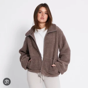  teddyjacka med dragkedja - !!!!PRISLAPPEN ÄR FORTFARANDE PÅ!, ALDRIG ANVÄNT!!Mysig brun teddyjacka med dragkedja framtill. Jackan har en avslappnad passform och långa ärmar, perfekt för kyliga dagar. Den har en hög krage och två fickor för extra komfort. 