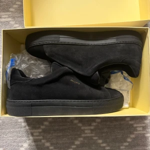 Svarta sneakers från Axel Arigato - Stilrena svarta sneakers i mocka från Axel Arigato. Skorna har en diskret design med elastiska band istället för snörning och en platt sula. Perfekta för en minimalistisk look. Priset pga att dem inte finns att köpa mer!!!